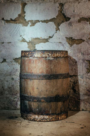 old oak barrels in the cellar in the stone wall backgroundの写真素材