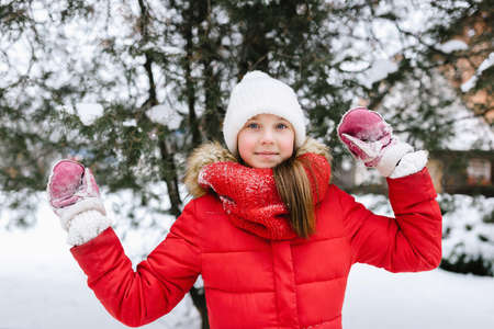 girl in a red jacket playing in snow in winterの写真素材