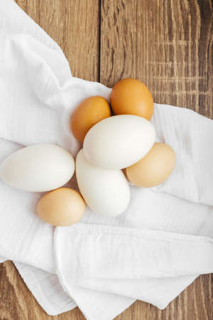 Chicken eggs on a white napkin on a wooden tableの写真素材
