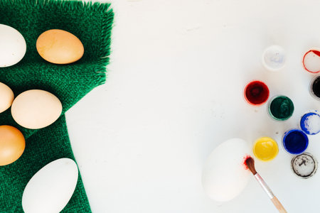 Eggs, paints and brush on a table on a green napkin. Preparation for Easter