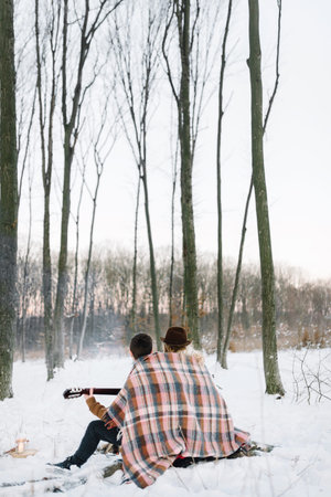 Young couple under the checkered blanket, the girl in a hat,