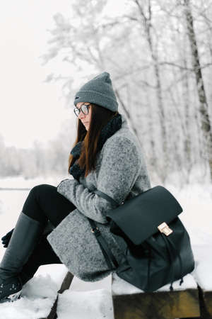 portrait of the brunette in glasses gray coat with a backpackの写真素材
