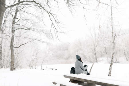 Portrait of a brunette in glasses gray coat with a backpack in the winter, the view zdaleka snowの写真素材