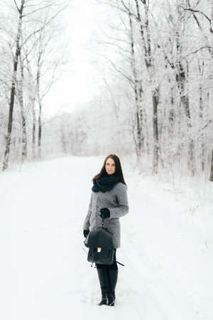 portrait of the brunette in glasses gray coat with a backpackの写真素材