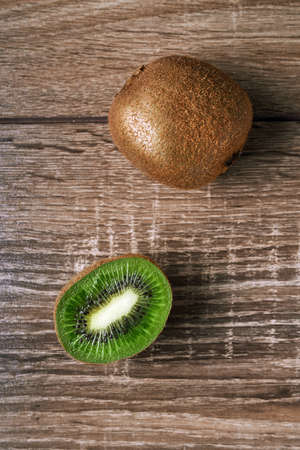 Ripe whole kiwi and half kiwi, isolated on a wooden backgroundの写真素材