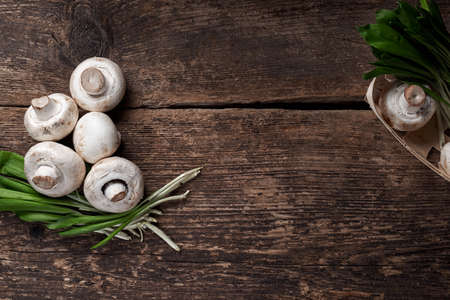Fresh white mushrooms champignon in brown bowl on wooden background. Top view. Copy space.の写真素材