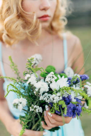 Portrait of a bright curly girl with flowers in a blue dressの写真素材