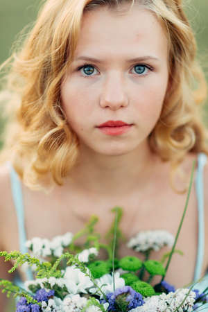 Portrait of a bright curly girl with flowers in a blue dressの写真素材