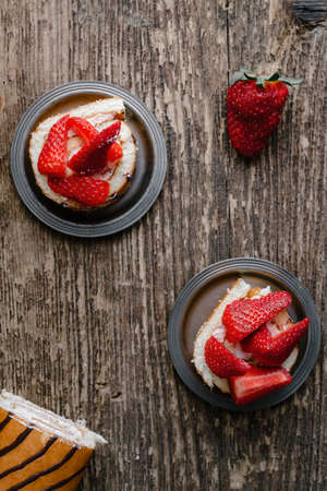 Homemade cake roll with strawberry cream on a wooden background, fresh strawberry berriesの写真素材