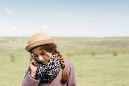 Young beautiful woman talking on the phone in nature. In the vintage style.の写真素材