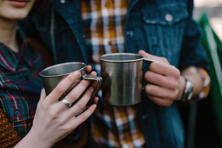 Hands of a young couple with travel mugs, a shirt in a cageの写真素材