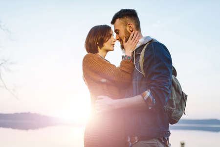 Young tourist couple in the setting sun on the background of a beautiful lakeの写真素材