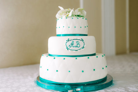 A multi-level white maroon wedding cake with white lilies on top