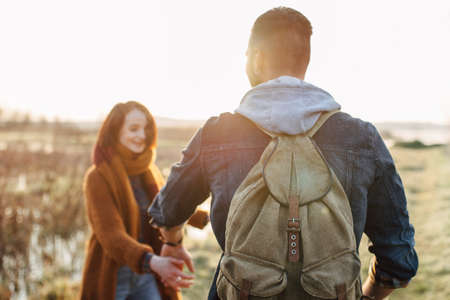 Young tourist couple in the setting sun against the backdrop of a beautiful lake with a telescopeの写真素材