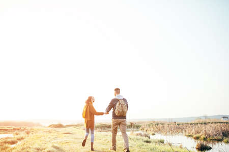 Young tourist couple in the setting sun against the backdrop of a beautiful lake with a telescopeの写真素材