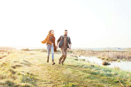 Young tourist couple in the setting sun against the backdrop of a beautiful lake with a telescopeの写真素材