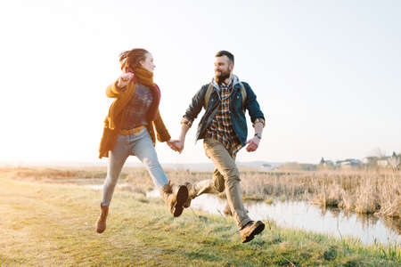 Young tourist couple in the setting sun against the backdrop of a beautiful lake with a telescopeの写真素材