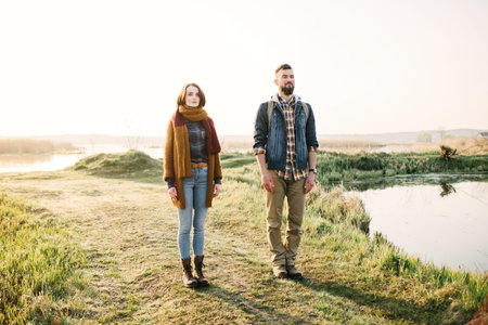 Young tourist couple in the setting sun against the backdrop of a beautiful lake with a telescopeの写真素材