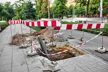 Repair of the sidewalk in the city, red white tapeの写真素材