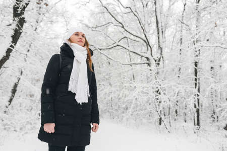 Beautiful young girl in a white fairy winter forest. walk in the fresh airの写真素材