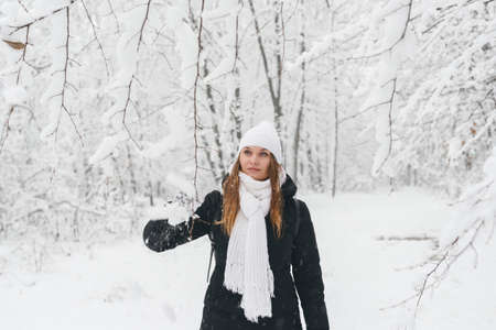 Beautiful young girl in a white fairy winter forest. walk in the fresh airの写真素材