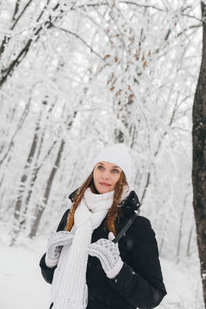 Beautiful young girl in a white fairy winter forest. walk in the fresh airの写真素材