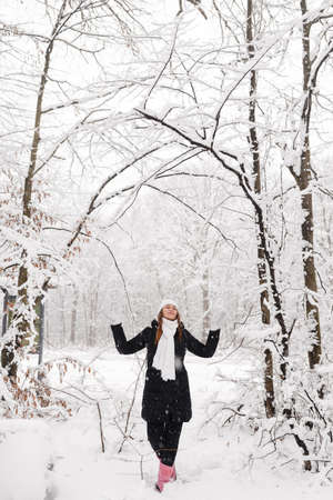 Beautiful young girl in a white fairy winter forest. walk in the fresh airの写真素材