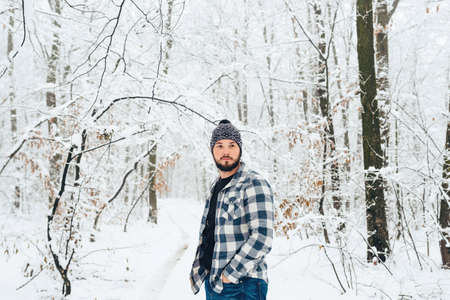 Handsome bearded man in a plaid shirt in the woods, in winterの写真素材