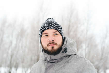 Outdoor portrait of a beautiful bearded man in a jacket and jeans. Casual winter fashionの写真素材