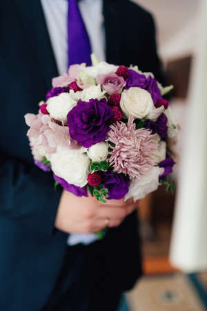 gorgeous wedding bouquet in purple tones in the hands of the groomの写真素材