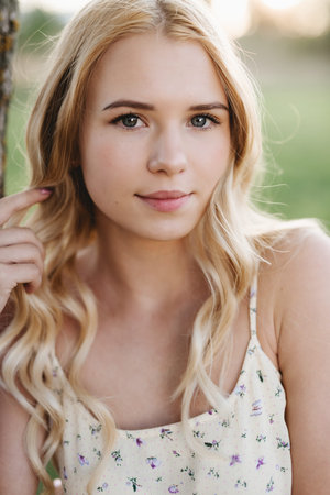 Beautiful woman portrait with fresh daily make-up blond curly hair and hands touching hairの写真素材