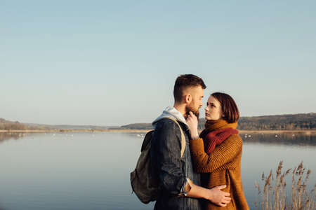 Young tourist couple in the setting sun on the background of a beautiful lakeの写真素材