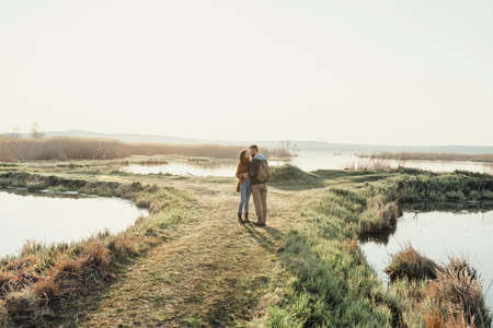 Young tourist couple in the setting sun on the background of a beautiful lakeの写真素材