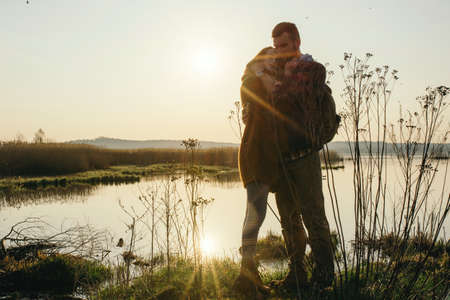 Young tourist couple in the setting sun on the background of a beautiful lakeの写真素材