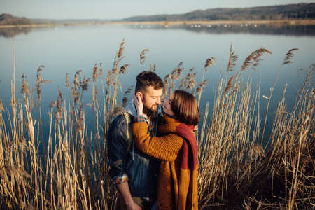 a young couple in love embraces, and fools around on the shore of the lake near the reeds. feelings, emotionsの写真素材