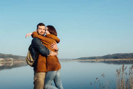beautiful young couple in hipster clothes hugging in the background beautiful blue lake, beautiful loving feelingの写真素材
