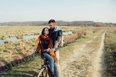 Romantic couple in love. Sunset. A boy and a girl are standing next to a bicycle in nature, sensibilities, emotionsの写真素材