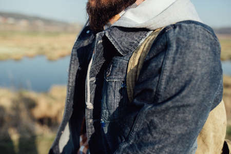 stylish hipster traveler with backpack, in the background of a Dutch lake, wildlife concept wanderlust and adventure with space for text. back view. atmospheric momentの写真素材