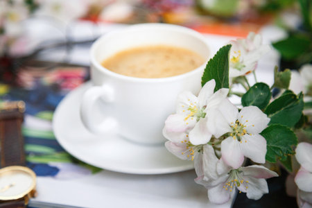 A coffee mug with a flowering branch and notes good morning on a blue country table from the top,...
