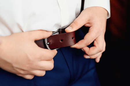 Hands of a business man fastening a beltの写真素材