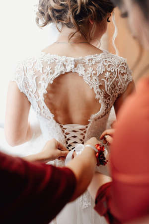 Wedding morning women's hands fasten the bride's corsetの写真素材