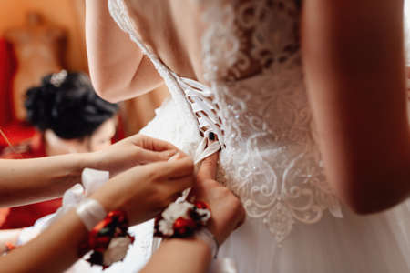 Wedding morning women's hands fasten the bride's corsetの写真素材