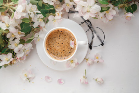 A coffee mug with a flowering branch and notes a good morning light underfoot view from above,...
