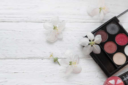 decorative cosmetics for the face, nail polish, white fresh flowers on a light wooden backgroundの写真素材