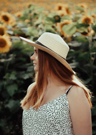 girl with hat, walking on the field of sunflowers, smiling beautiful smile, cheerful girl, style, lifestyle, ideal for advertising and photo the sun is shining bright and juicyの写真素材