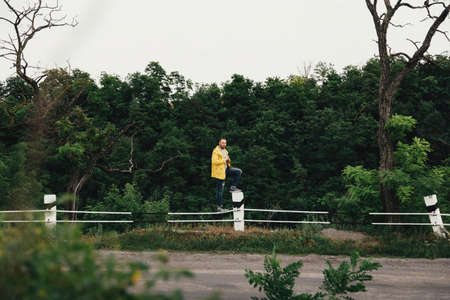 a man in a yellow raincoat with a camera, against a background of rocksの写真素材