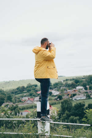 a man in a yellow raincoat with a camera, against a background of rocksの写真素材