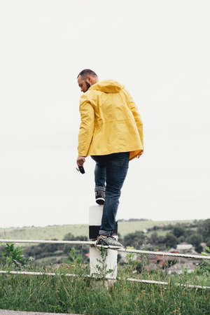 a man in a yellow raincoat with a camera, against a background of rocksの写真素材