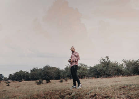 Portrait of a beautiful bearded young man in a checkered shirt, photographed in nature, and taking picturesの写真素材