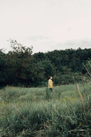a man in a yellow raincoat with a camera, against a background of rocksの写真素材
